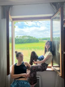 Hannah and her sister sitting on a balcony with sunflower fields behind them